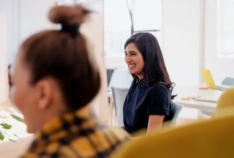 Photo d'une jeune femme souriante pendant une réunion de bureau.